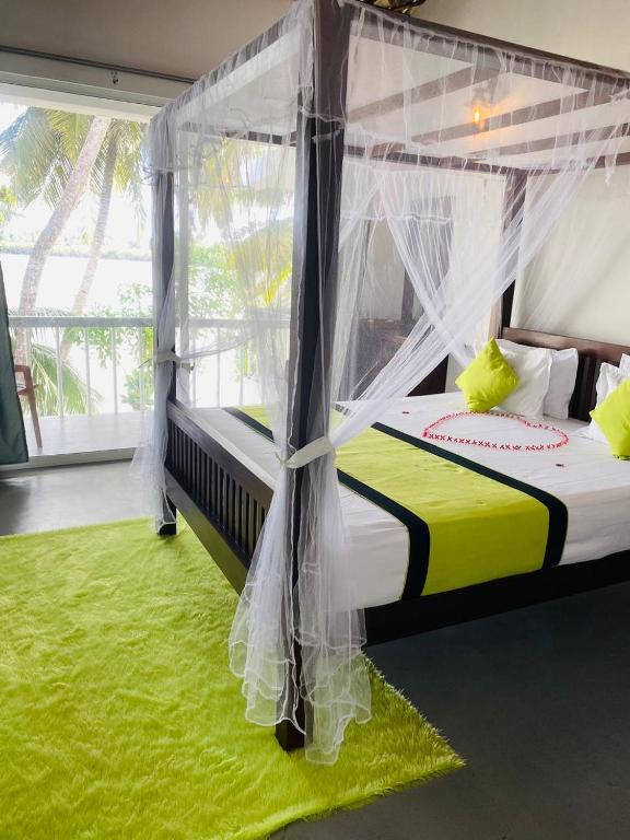 a bedroom with a canopy bed with a green rug at Lake Duwa Hotel in Ambalangoda
