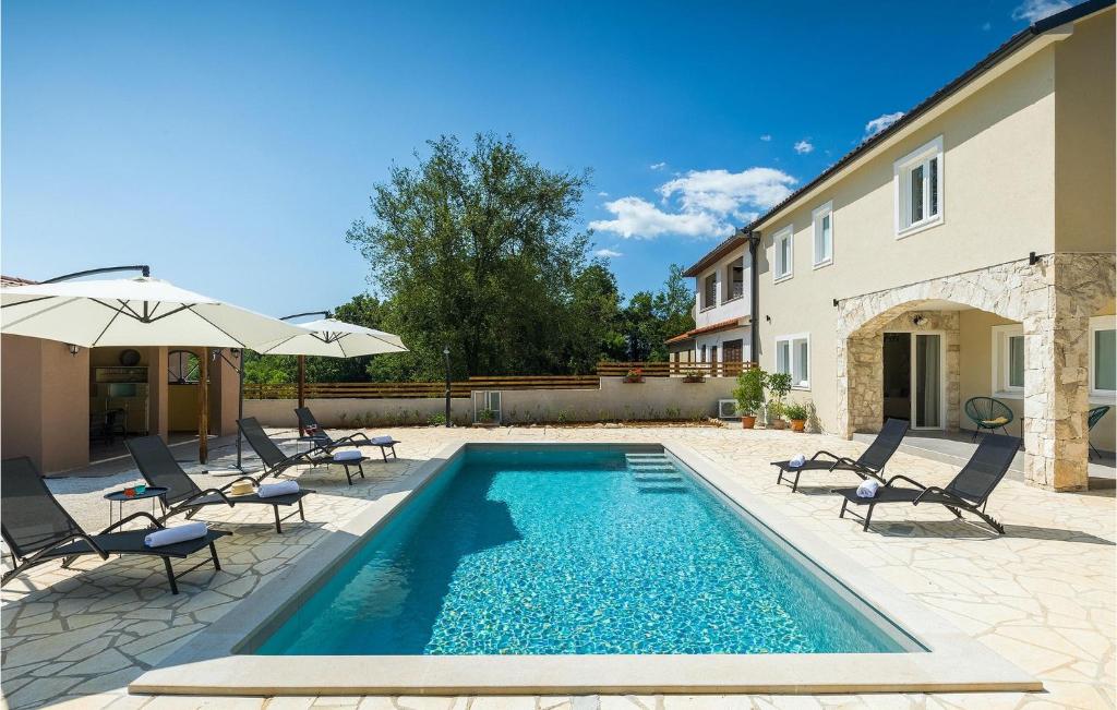 a pool with chairs and umbrellas next to a house at Villa Stora Kuca in Krapan