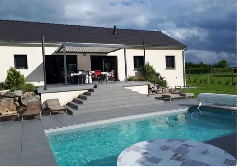 a house with a swimming pool in front of a house at maison rue de la plage in Lanobre