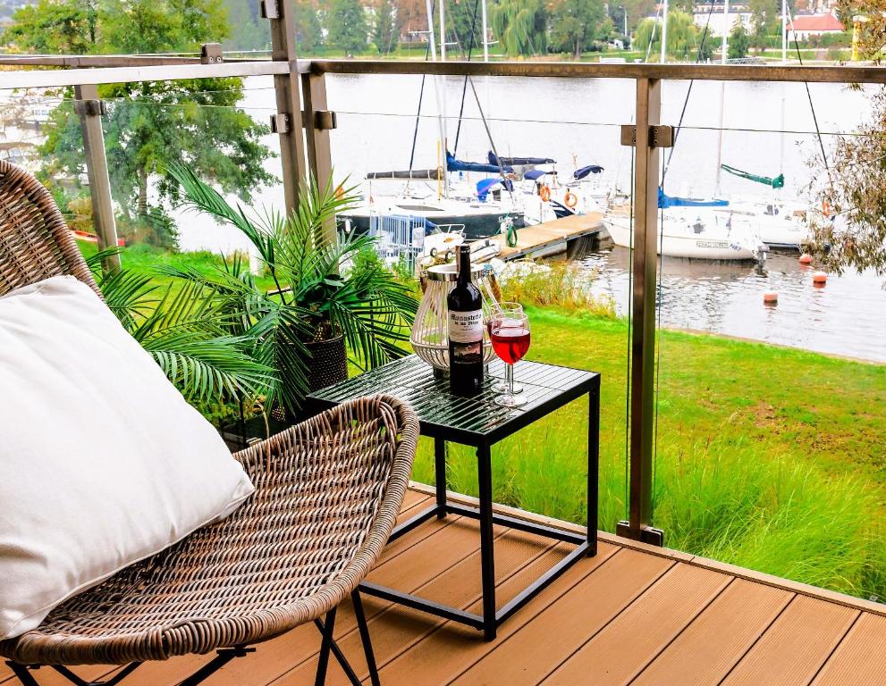 a table with two glasses of wine on a porch at Marina Relax - widok na jezioro, parking podziemny, winda, Netflix, TV55" in Iława