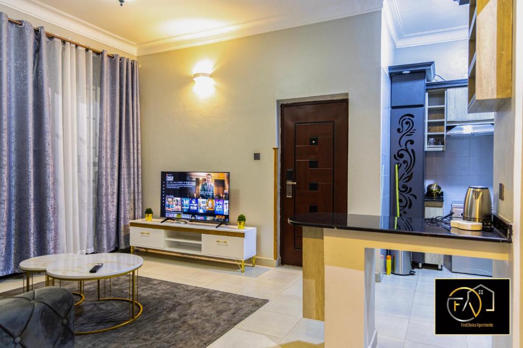 un soggiorno con televisione e tavolo di FirstChoice apartments Kampala a Kampala