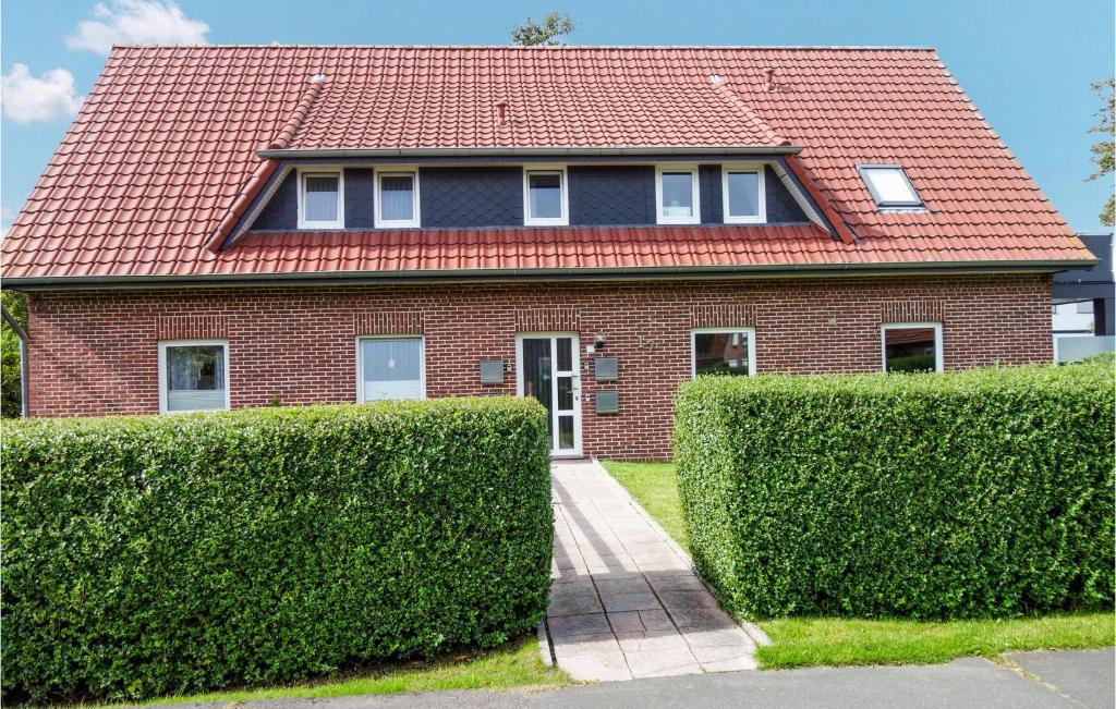 ein Backsteinhaus mit rotem Dach und zwei Büschen in der Unterkunft Lovely Apartment In Butjadingen in Butjadingen