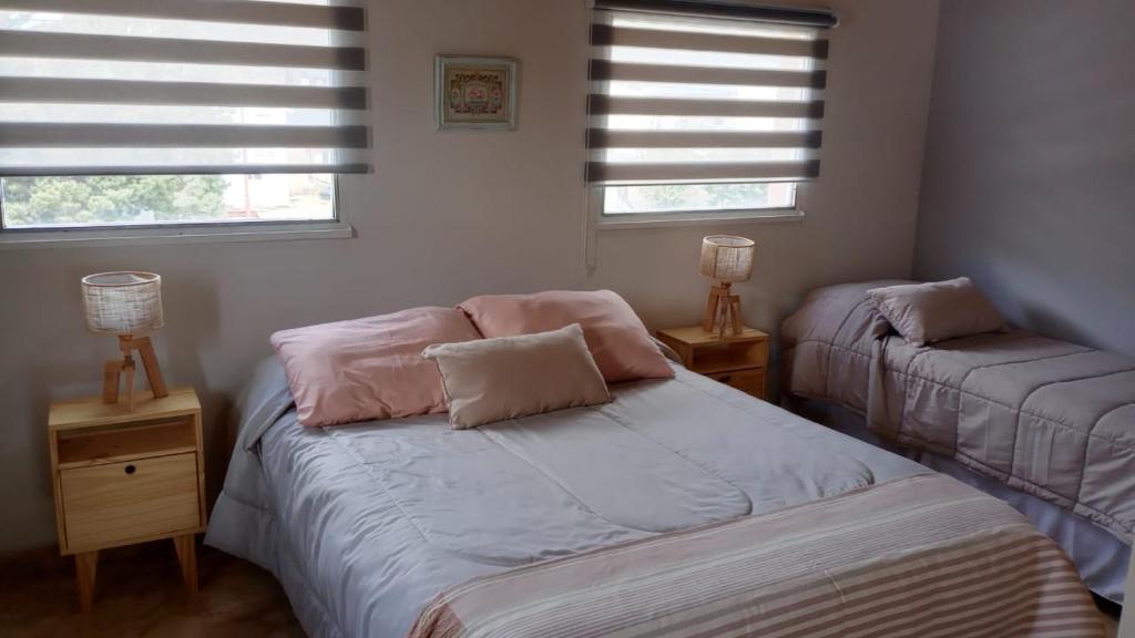 a bedroom with two beds and two windows at Alta Montaña Apart in El Chalten