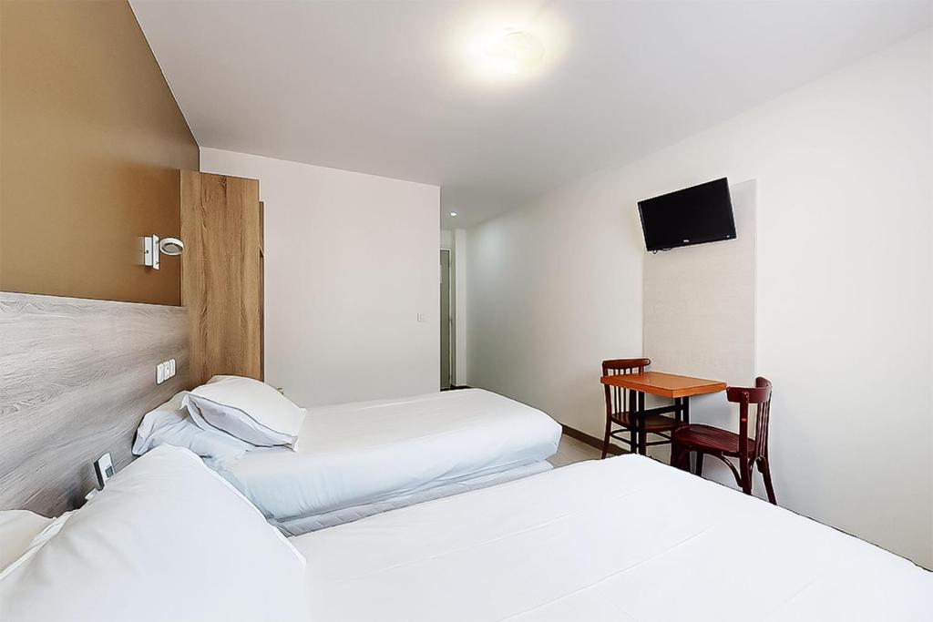 a hotel room with two beds and a table at Hôtel de Ménilmontant in Paris