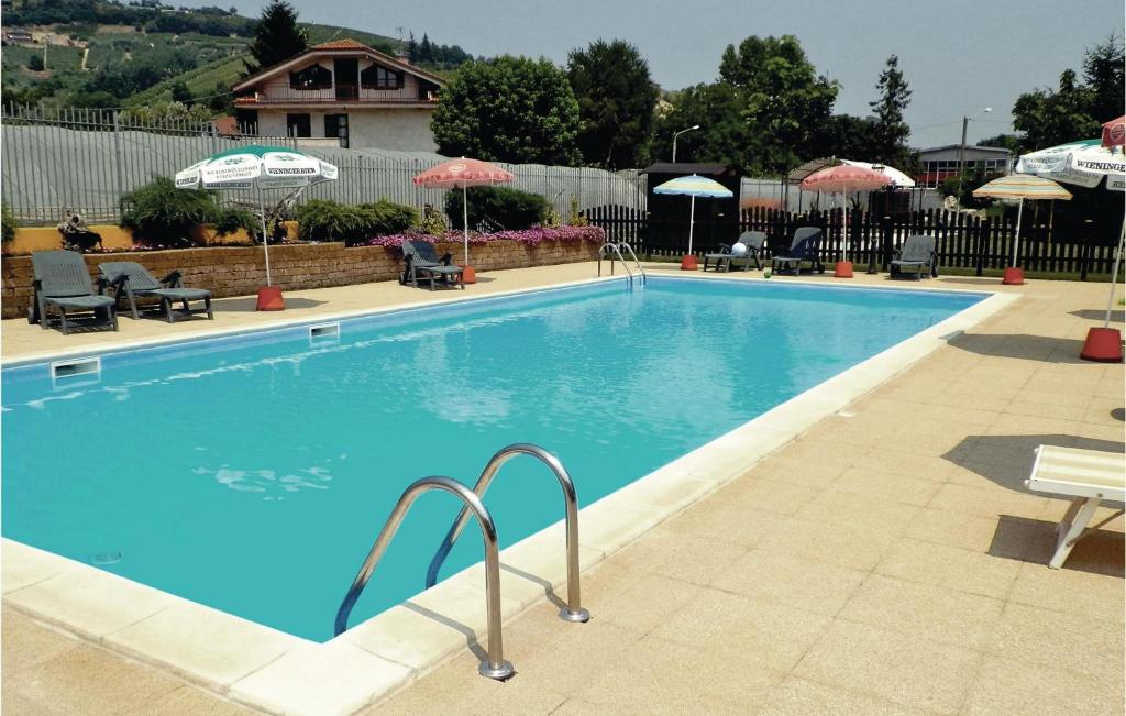a large swimming pool with chairs and umbrellas at Le Rocche 1 in Cisterna dʼAsti