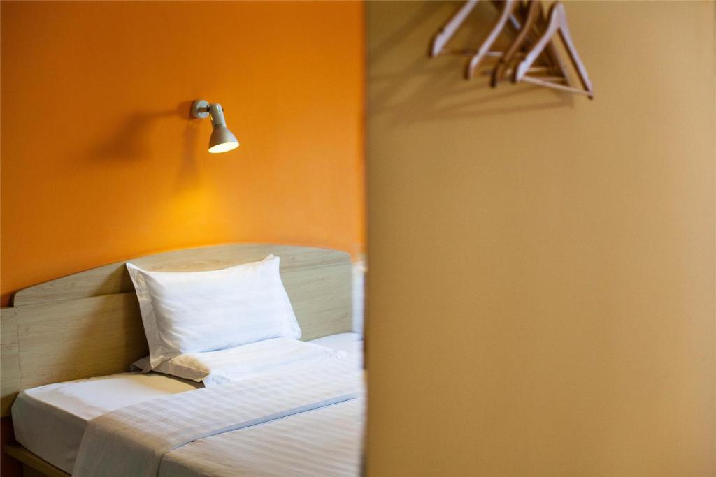 a bedroom with a bed with an orange wall at 7Days Inn Xi'an Xishao Gate Laodong Road Railstation in Xi'an