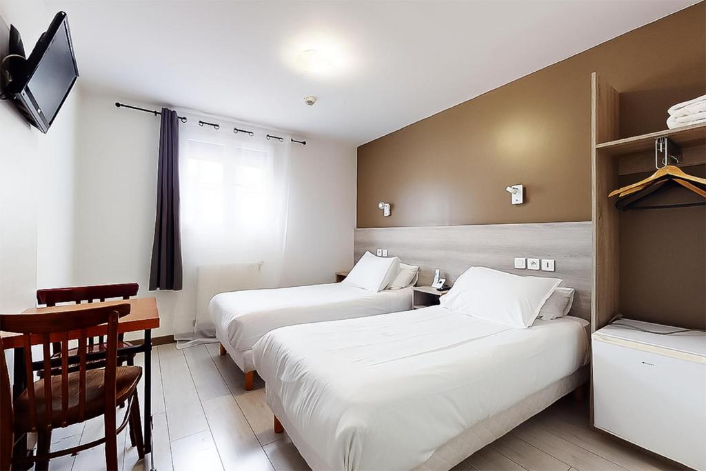 two beds in a room with a table and a desk at Hôtel de Ménilmontant in Paris