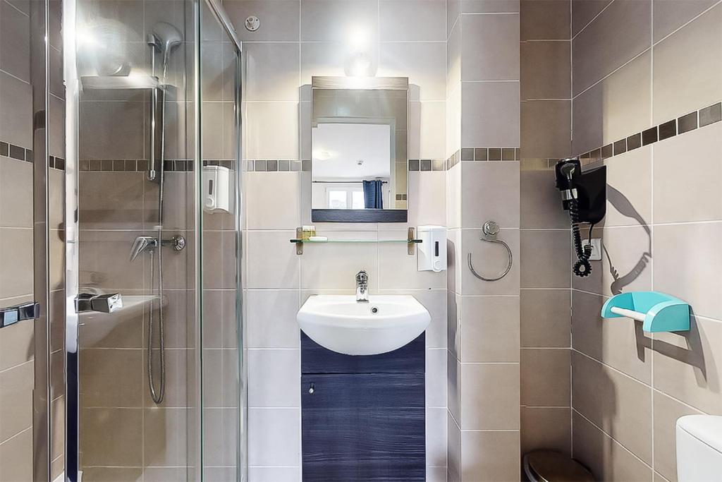 a small bathroom with a sink and a shower at Hôtel de Ménilmontant in Paris