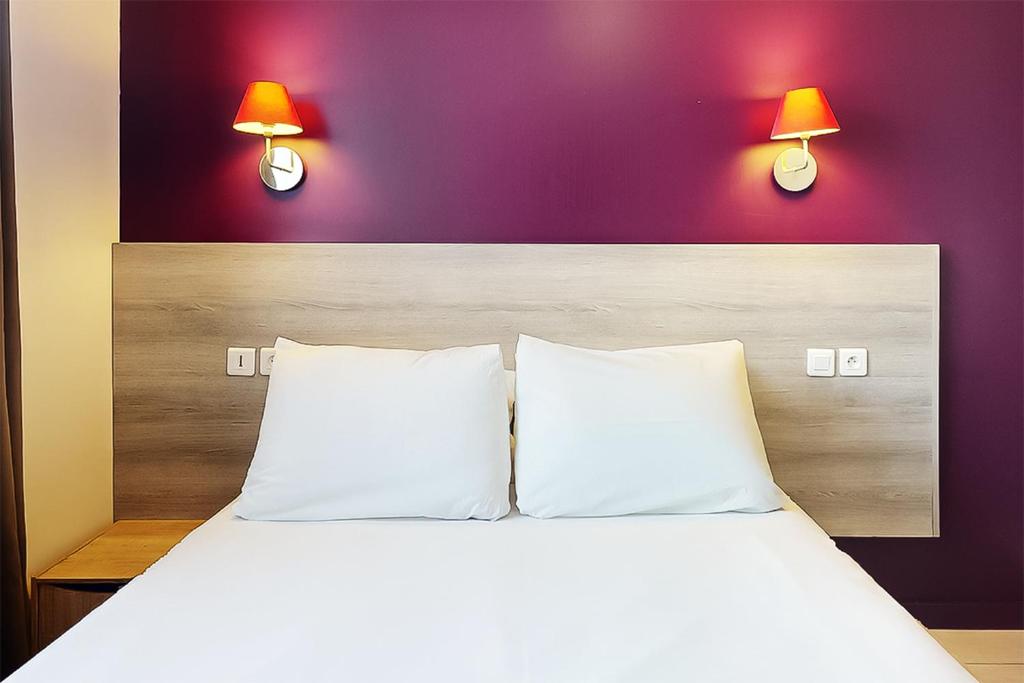 a bedroom with a bed with two lamps on the wall at Hôtel de Ménilmontant in Paris