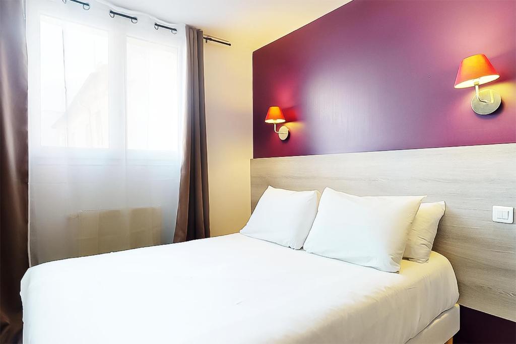 a bedroom with a bed and a purple wall at Hôtel de Ménilmontant in Paris