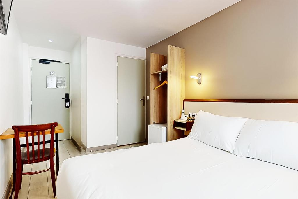 a bedroom with a white bed and a desk at Hôtel de Ménilmontant in Paris