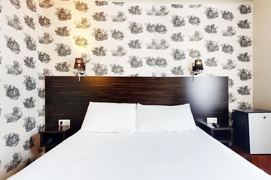 a bedroom with a bed with a black and white wallpaper at Hôtel de Ménilmontant in Paris
