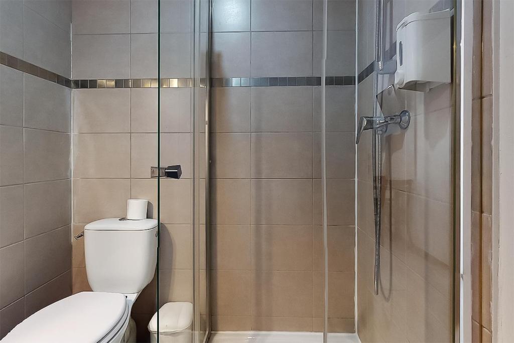 a bathroom with a toilet and a glass shower at Hôtel de Ménilmontant in Paris