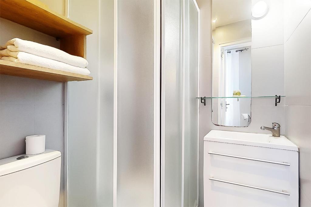 a white bathroom with a toilet and a sink at Hôtel de Ménilmontant in Paris