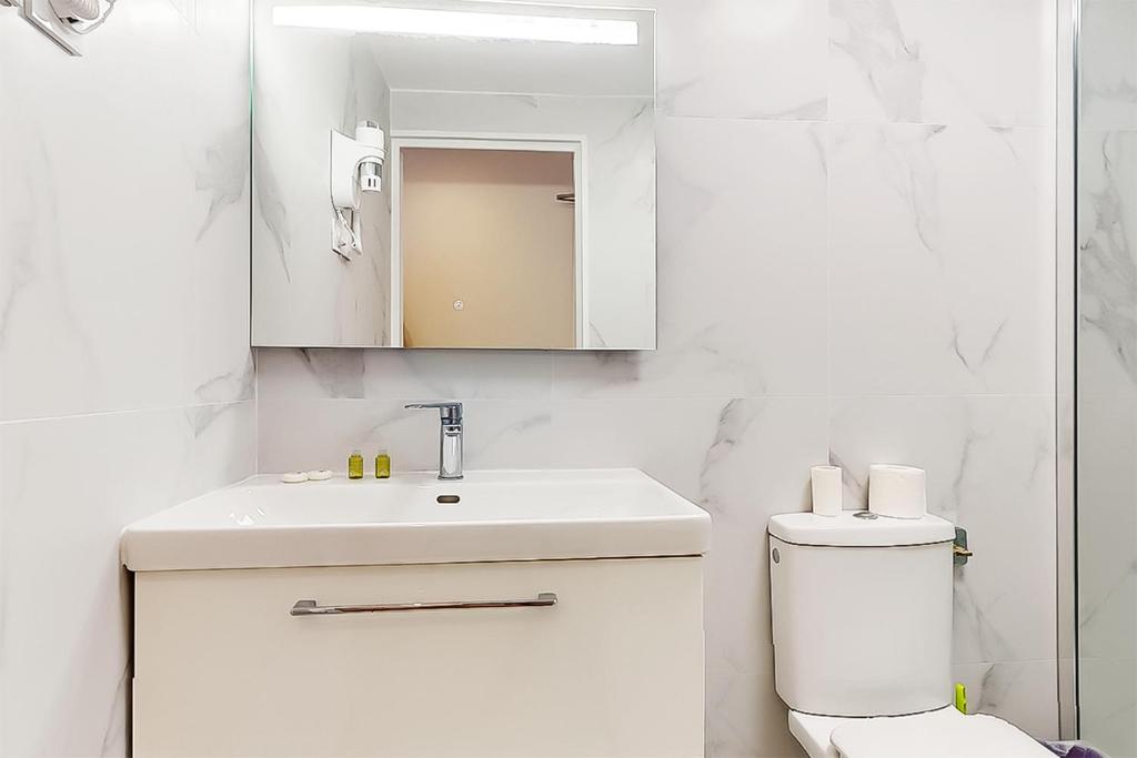 a white bathroom with a sink and a toilet at Hôtel de Ménilmontant in Paris