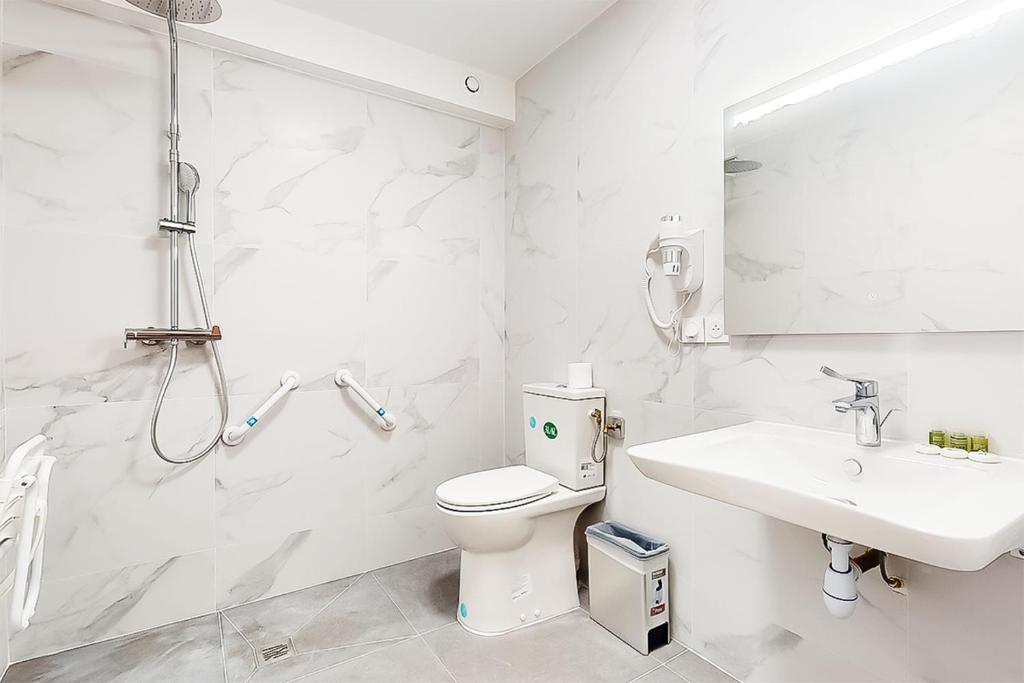 a white bathroom with a toilet and a sink at Hôtel de Ménilmontant in Paris
