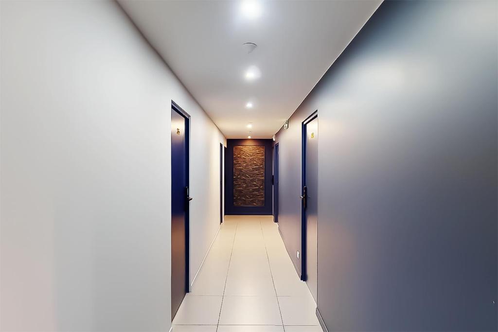 a hallway with two doors and a tile floor at Hôtel de Ménilmontant in Paris