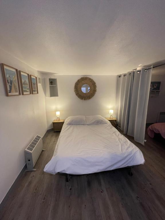une chambre avec un grand lit blanc avec deux lampes dans l'établissement Plage et commerces à 50m, sans télé pour déconnecter !, à Houlgate