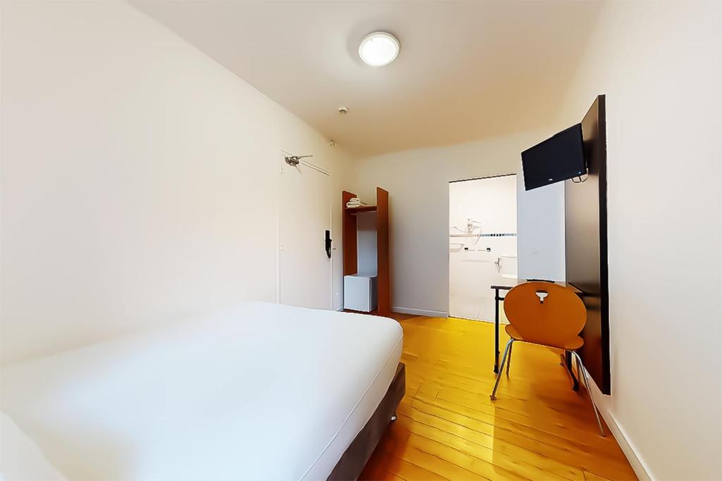 a bedroom with a bed and a table and a television at Hôtel de Ménilmontant in Paris