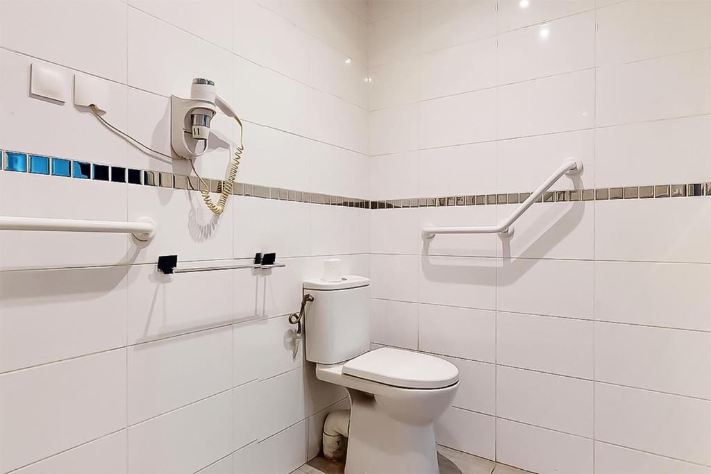 a white bathroom with a toilet and a phone at Hôtel de Ménilmontant in Paris