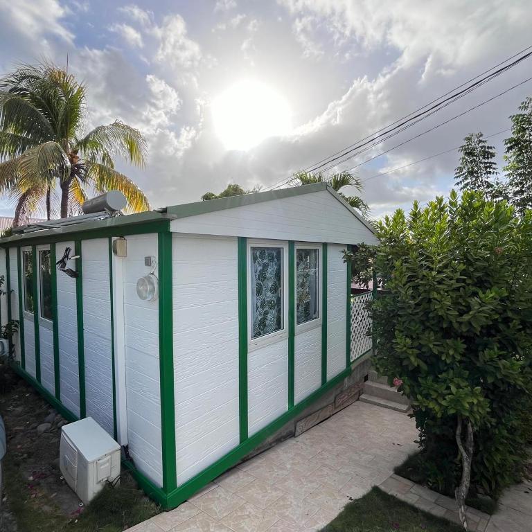 a small house with green and white paint on it at Gîte créole, apéro offert, plage à 5min in Vieux-Habitants
