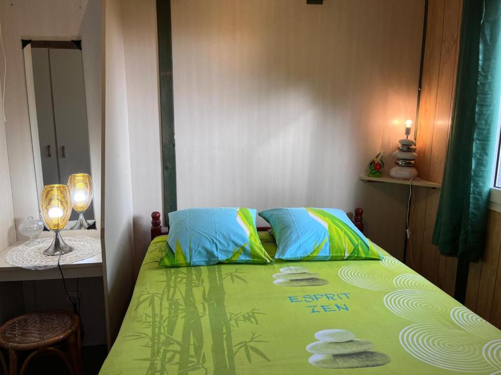 a bedroom with a green bed with towels on it at Gîte créole, apéro offert, plage à 5min in Vieux-Habitants