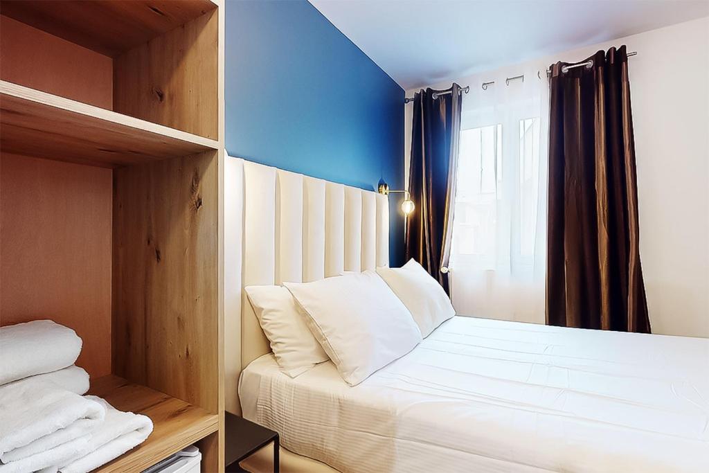 a bedroom with a white bed and a window at Hôtel de Ménilmontant in Paris