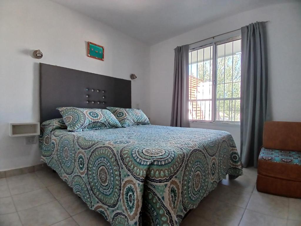 una camera da letto con un letto con una coperta e una finestra di RUTAC DEPARTAMENTOS- Departamento moderno con balcón a Las Grutas