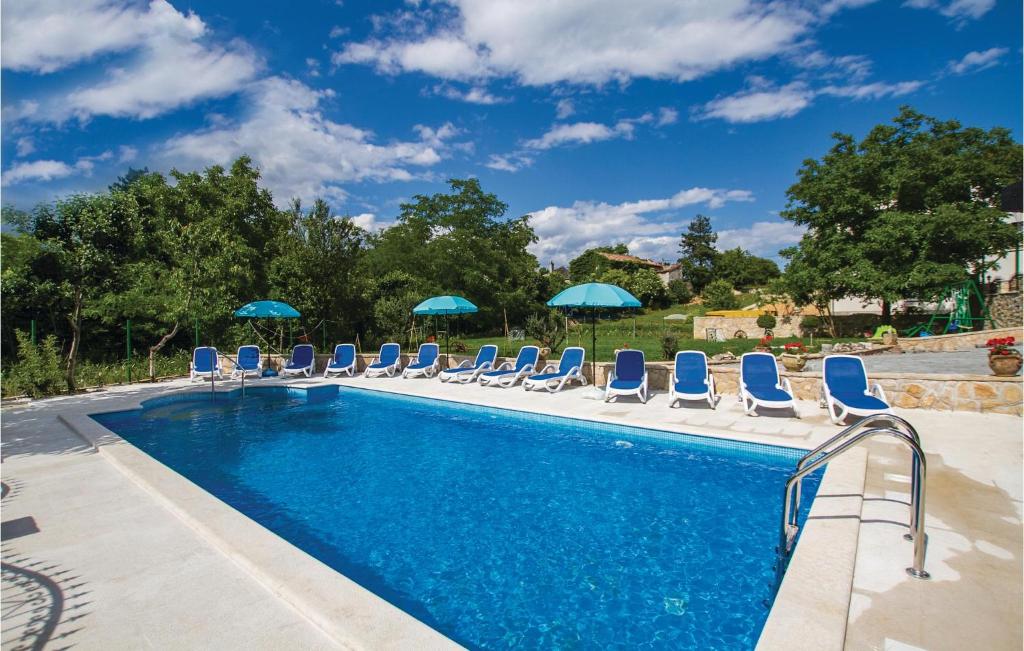 ein Swimmingpool mit blauen Stühlen und Sonnenschirmen in der Unterkunft Holiday Home Nedescina 49 in Nedeščina