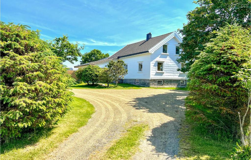 a white house with a dirt road in front at Vesthassel-Nesheim in Borhaug