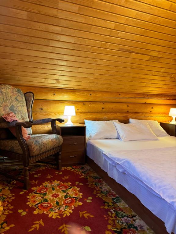 a bedroom with a bed and a chair and lamp at Cottage Karinka in Bukovel