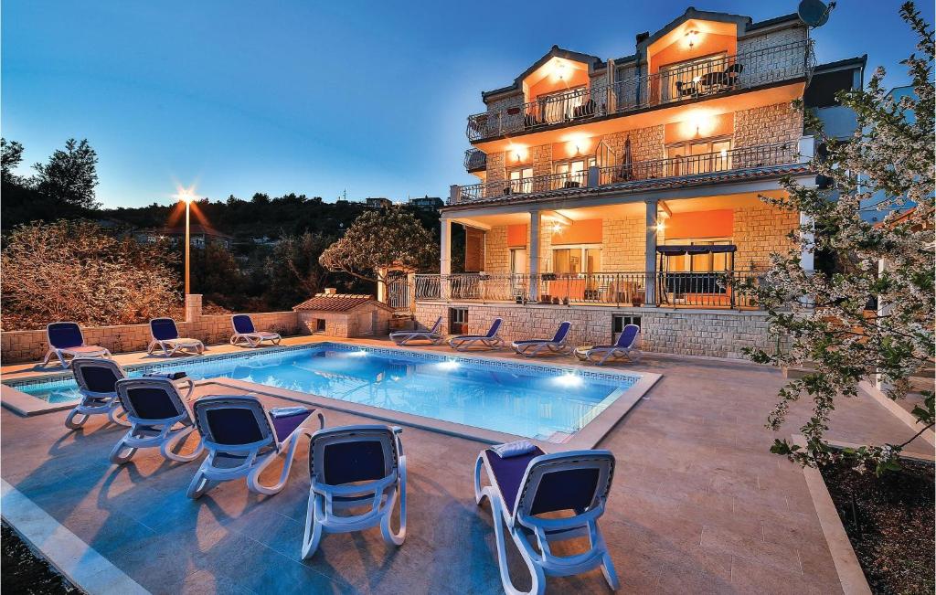 a swimming pool with chairs and a house at Nice Apartment In Poljica in Poljica