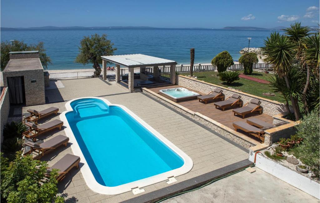 a swimming pool with chairs and the ocean in the background at Amazing Home In Podstrana in Podstrana