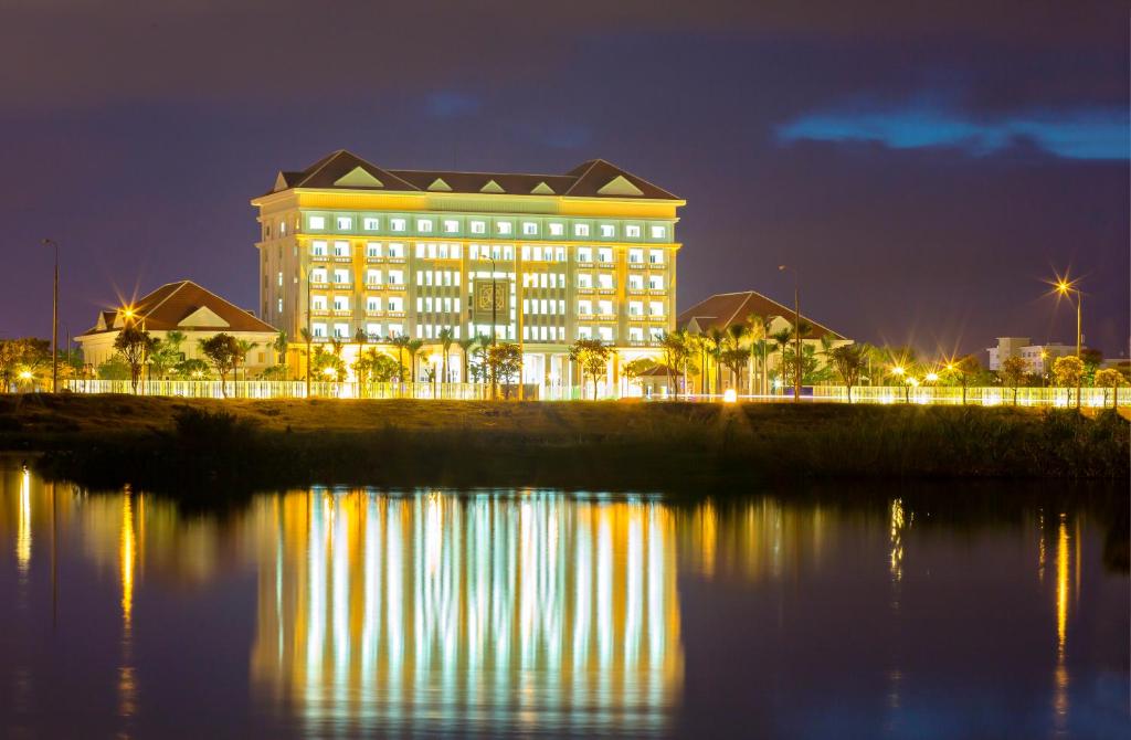 un edificio con luces reflectantes en el agua por la noche en Ban Thach Riverside Hotel & Resort en Tam Kỳ