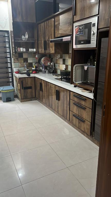 a kitchen with wooden cabinets and a microwave at Doctor's House in Lahore