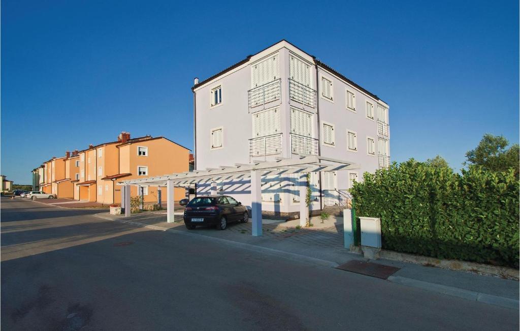 une voiture garée devant un grand bâtiment blanc dans l'établissement Apartment Vodnjan Peroj Ii, à Vodnjan