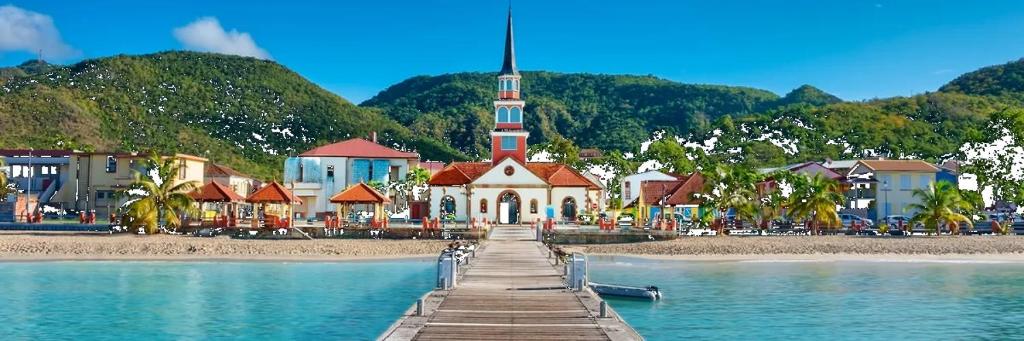 una iglesia en una playa con un muelle en el agua en Villa pour 4 à 8 personnes près des plages du Sud & Marina du Marin - Wi-Fi sur demande, en Le Marin