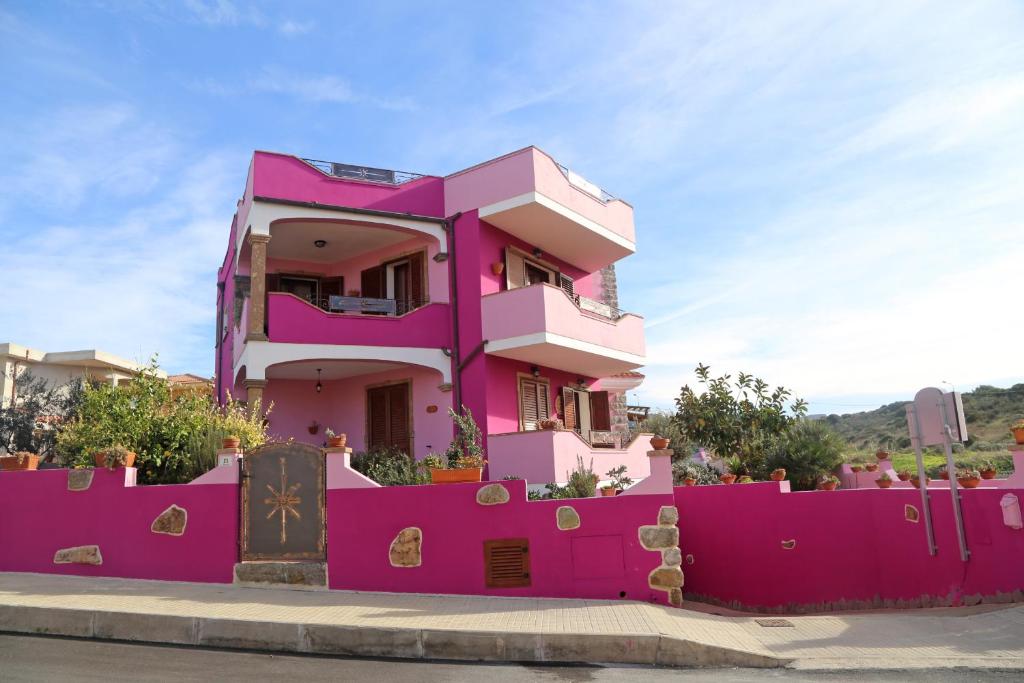 a pink house in front of a pink fence at La Fortezza casa vacanze & appartament in Castelsardo