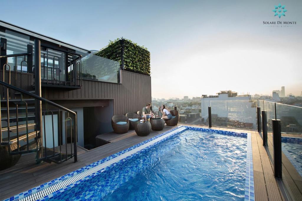 ハノイにあるSolare De Monte Hotel & Spaの建物のプールの横に座っている二人