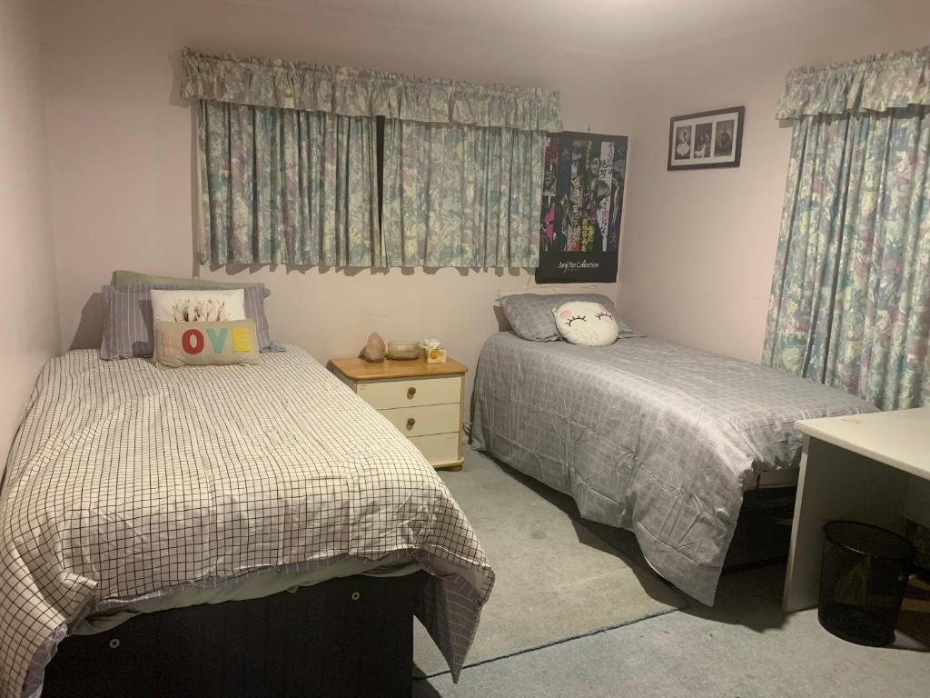 a bedroom with two beds and a desk and curtains at RUs Terraces in Kauri