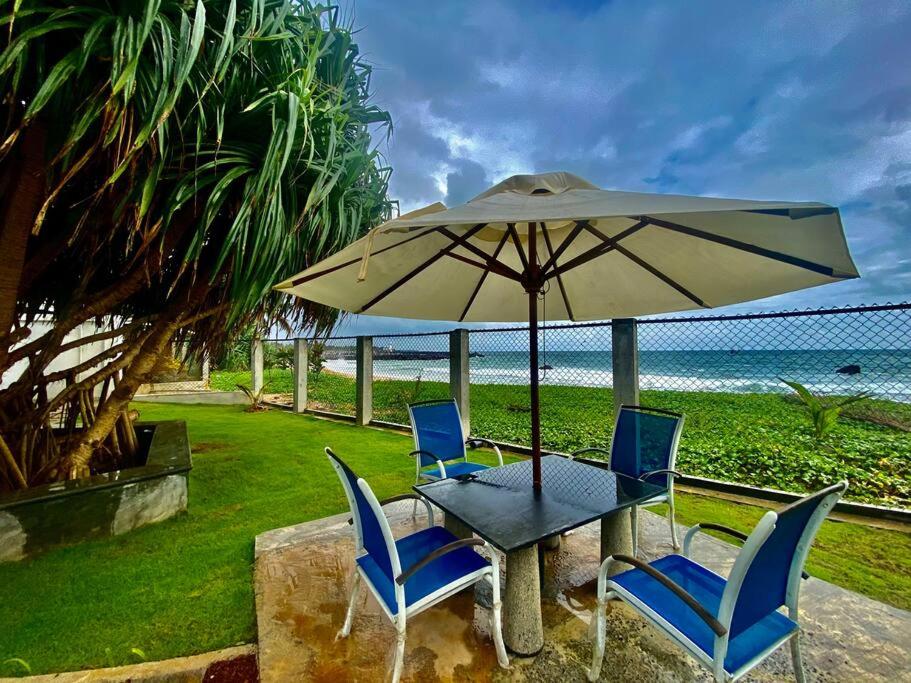 un tavolo e sedie sotto un ombrellone in spiaggia di Villa 59- Luxurious Beach house in Ambalangoda a Ambalangoda