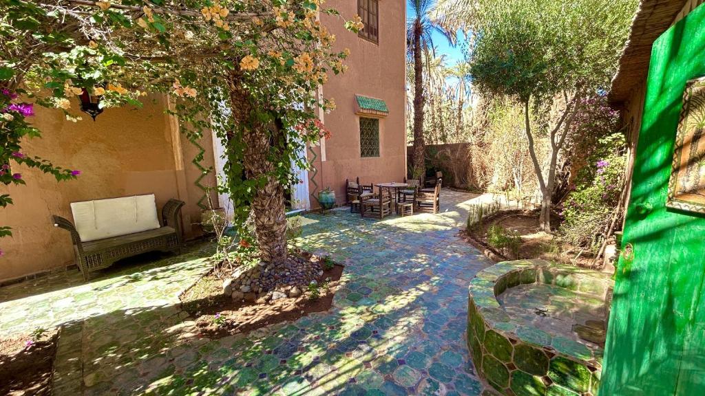 a garden with a tree and a bench and a building at Dar Nakhla - Guest House In Zagora - Restaurant & Desert Excursions in Zagora