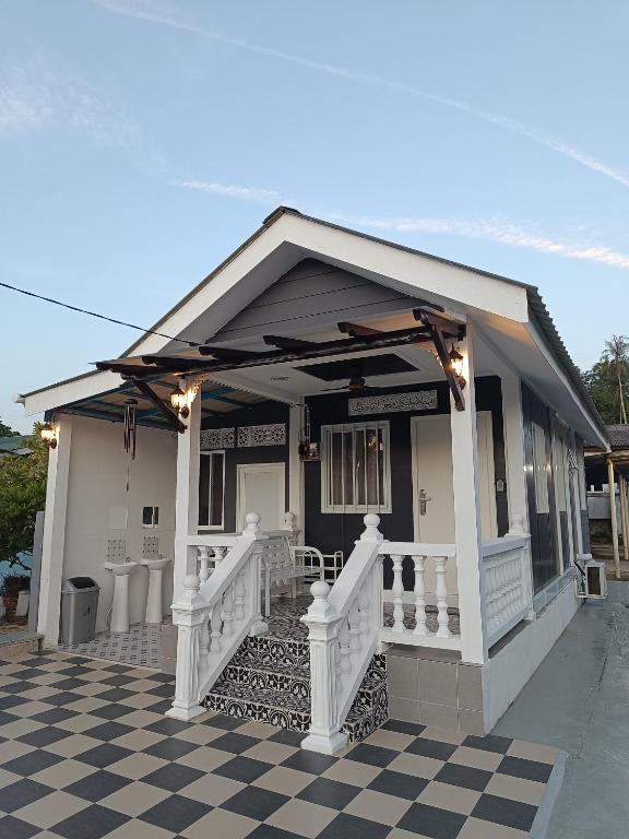 a white house with a porch and a checkered floor at SKY Homestay in Kota Bharu