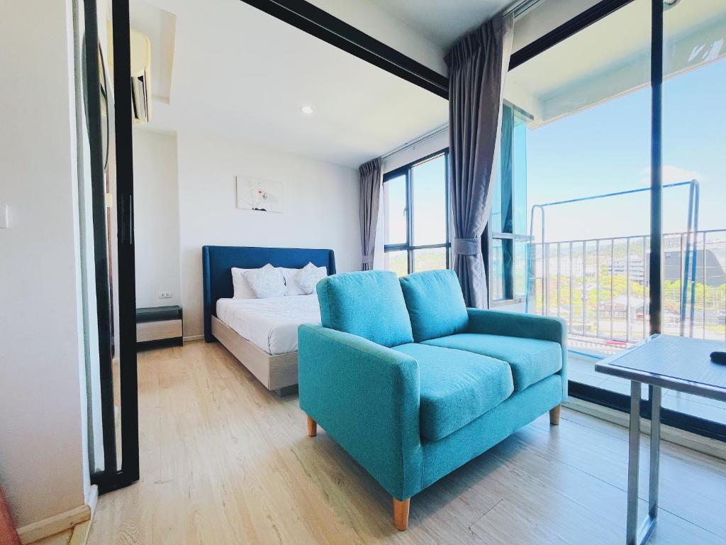 1 dormitorio con silla azul, cama y ventana en 04near Shopping Malls and Naka night market, en Phuket