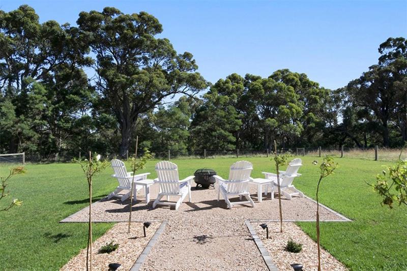a group of white chairs and a grill in a field at Black Swan Retreat in Metung