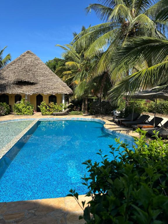 a swimming pool in front of a resort with palm trees at Kiwengwa Bungalow Boutique Resort in Kiwengwa