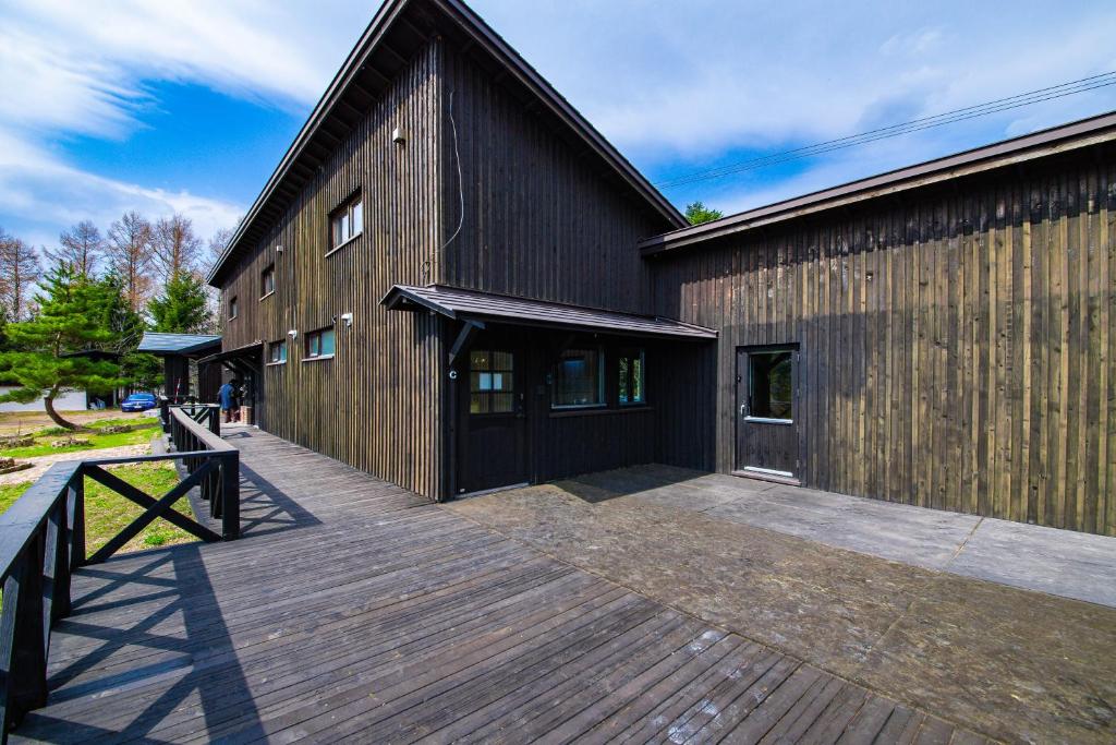 a large wooden building with a wooden deck at FamC in Nakafurano