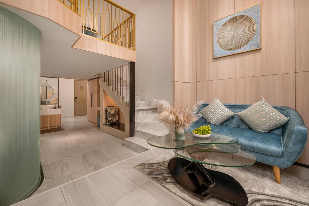 A blue sofa lounge with a glass coffee table beside an open staircase and hallway.