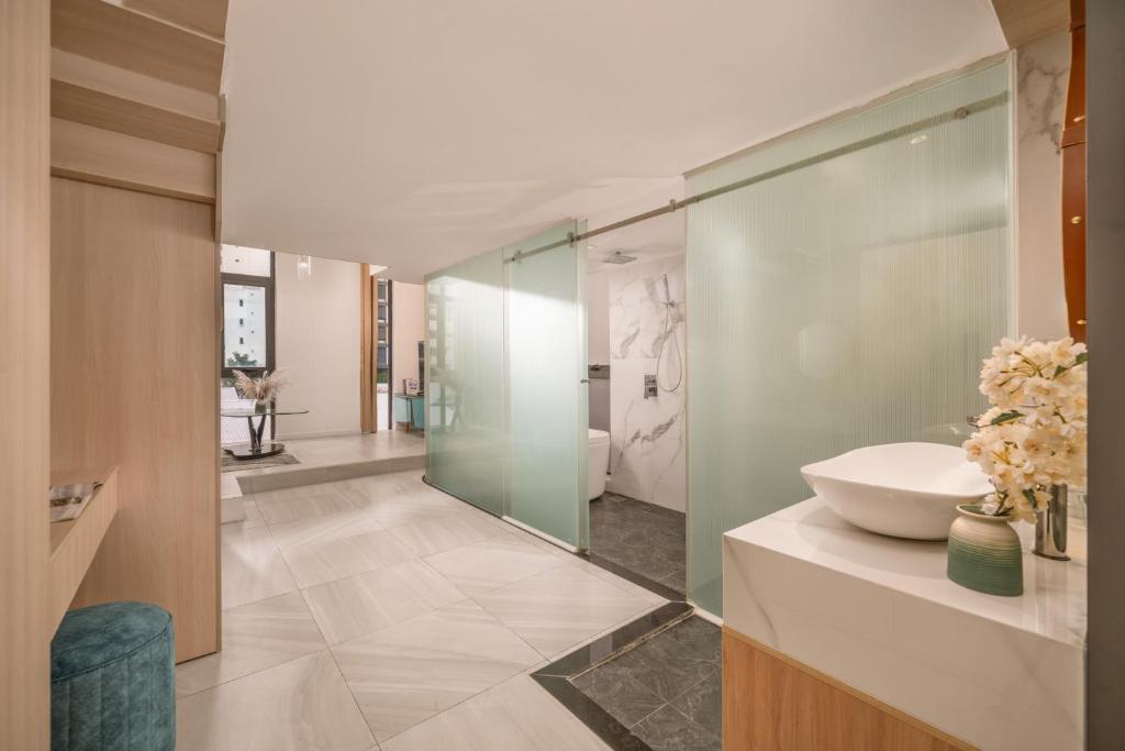 A spacious contemporary bathroom with a vessel sink, open shower and translucent glass partitions.