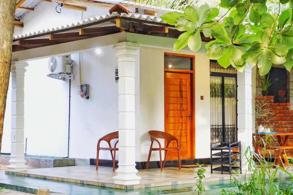 a house with two chairs on the porch at Sunrise Villa Pidurangala in Sigiriya